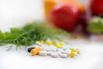 The heap of tablets, drugs lies against the background of fresh vegetables