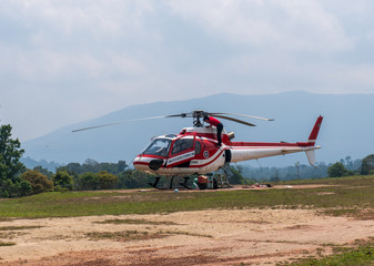 Fototapeta na wymiar Red Helicopter on Helipad for helicopter landing surrounded with lush green jungles