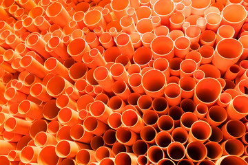 orange PVC pipes stacked in construction site