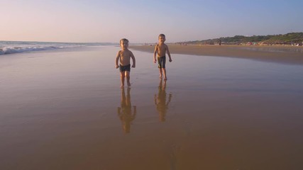 Slow motion - Two little brothers running, playing and enjoying while the camera chase them smiling and laughing