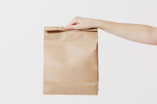 Close Up Female Holds In Hand Brown Clear Empty Blank Craft Paper Bag For Takeaway Isolated On White Background. Packaging Template Mockup. Delivery Service Concept. Copy Space. Advertising Area.