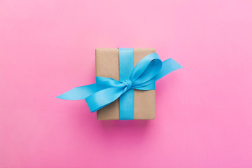 gift wrapped and decorated with blue bow on pink background with copy space. Flat lay, top view