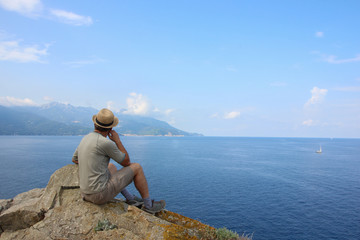 Fototapeta na wymiar Man with straw hat enjoying the view in Elba island, Enfola headland, Italy