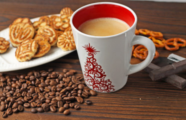 A cup of coffee, grains of coffee and cookies on a wooden table.