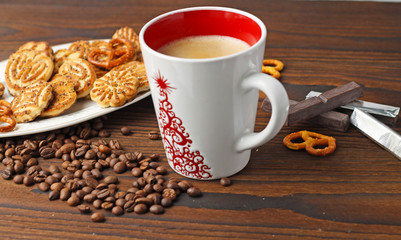 A cup of coffee, grains of coffee and cookies on a wooden table.