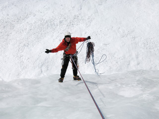 male mountain ice climber rapelling off a steep and long frozen waterfall in the Swiss Alps in deep winter not happy with problems he has with the climbing ropes