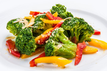 Dietary broccoli with vegetables and peanuts. On a white plate.