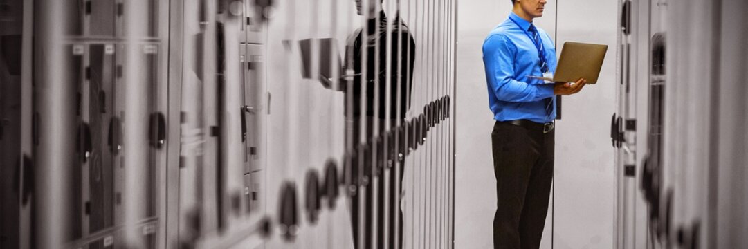 Technician using laptop while analyzing server