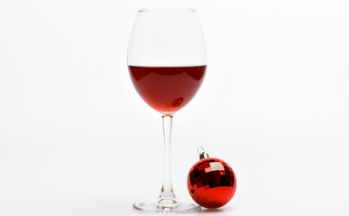 Winter celebration with alcohol drink. New year party concept. Glass with wine and christmas decoration. Wineglass with red liquid or wine and christmas ball ornament isolated on white background