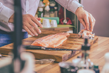 Unrecognizable chef preparing salmon in the kitchen.
