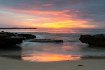 Fototapeta premium Sunrise at Pretty Beach, Australia. Reflections and colour over the ocean.