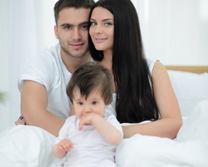 Happy couple and son sitting in bed