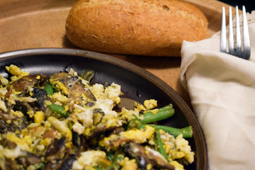 Fried champignons, green beans and eggs on the served table. Ready meal on a wooden dish. Selective focus.