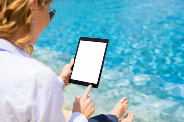 Businesswoman using tablet computer by the pool