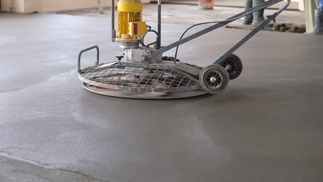 the workers grind the concrete floor at the construction site