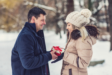 Man gives a box with a gift to his girlfriend, romantic surprise for Christmas.
