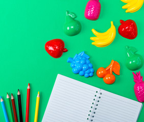 open notebook with empty white sheets and multicolored wooden pencils