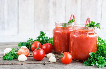 tomato juice in glass jars with cherry tomatoes on a wooden table
