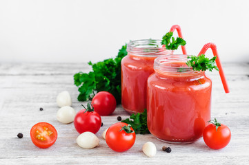 tomato juice in glass jars with cherry tomatoes on a wooden table