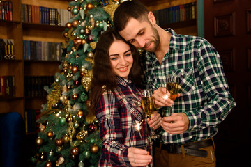 Merry Christmas and Happy New Year! Attractive young couple is celebrating holiday at home together, drinking champagne and smiling with Bengal lights in hand