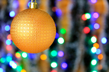 Golden hanging ball, christmas decoration with blurred lights background.