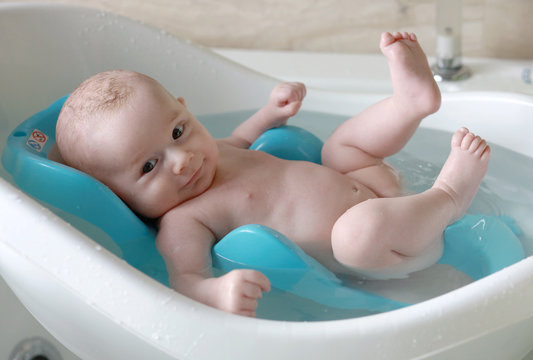 B&eacute;b&eacute; gar&ccedil;on blond dans son bain tout content avec un grand sourire