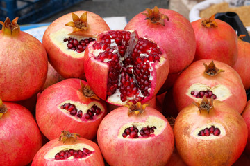 Pomegranate is sold in local market. Red fruit in cut lie on counter. Useful fruit with lots of vitamins and microelements.