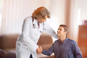 Obraz premium Friendly Senior doctor handshaking with young patient