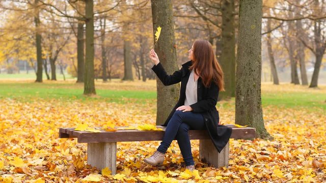 Woman look on yellow fallen leaf in her hand