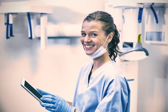 Smiling dental assistant using digital tablet - Powered by Adobe