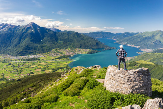 Hiker on top of Monte Berlinghera looks towards Colico and Monte Legnone, Sondrio province, Lombardy