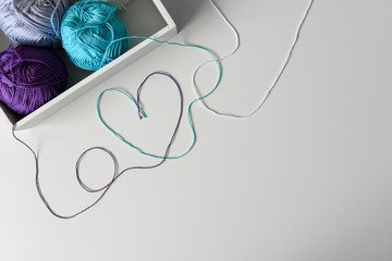 Creative way to design colorful cotton threads to make love word and heart on white background with copy space..