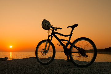 Fototapeta premium Silhouette of mountain bike on sunset at the seacoast