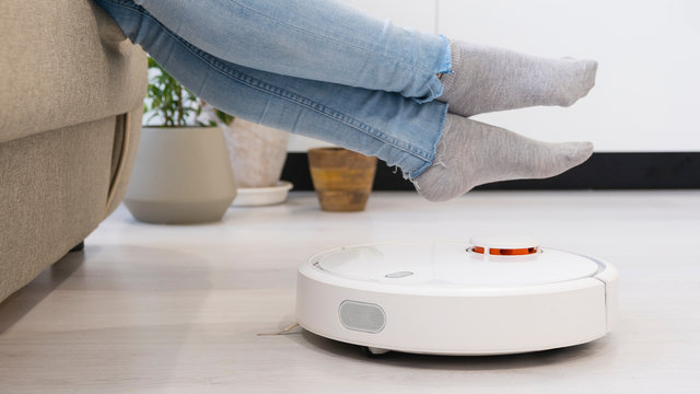 girl resting at home on the couch, while the robot vacuum cleaner. Time for yourself. smart House.