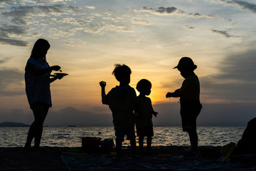 The silhouette of kids and mother at the beach in evening.