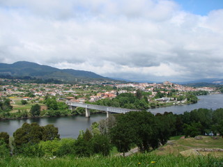 Panorama of a modern bridge connecting two countries, against a background of cloudy sky and mountain ridge on the horizon.