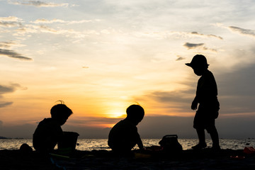 The silhouette brothers are playing together at the beach.