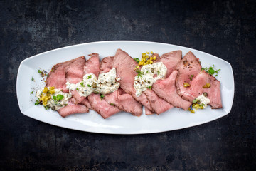 Traditional lunch meat with sliced cold cuts roast beef and remoulade as top view on a white plate