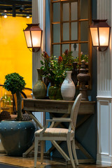 Vintage wooden chair and flower in ceramic vase with retro wall lamp interior decoration