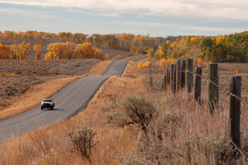 White Truck Driving on Black Top in Rural Wyoming in the Fall