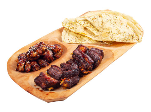 beer snack on the wooden plate. grilled pork ribs and chicken wings with italian pita bread chips