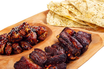 beer snack on the wooden plate. grilled pork ribs and chicken wings with italian pita bread chips
