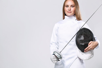 Young fencer athlete wearing fencing costume holding the sword and mask. Isolated on white...