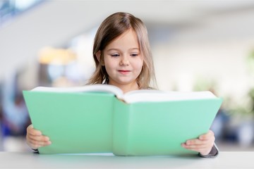 Adorable young girl reading a book