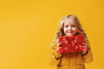Happy little girl preschooler in a winter jacket is holding a bo