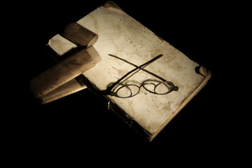 Obraz premium Closeup very old specacles eyes glasses with wooden box on very old open book lying on mirror for reflection