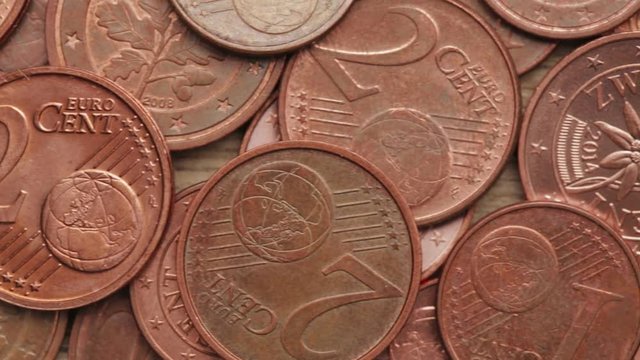 Closeup dolly footage of Euro cent coins over a wooden surface.