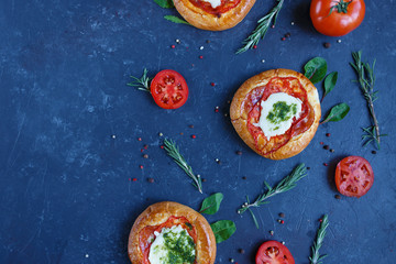 Homemade Mini Pizza with Tomatoes, Cheese and Bacon, Injuries and Spices on Dark Background
