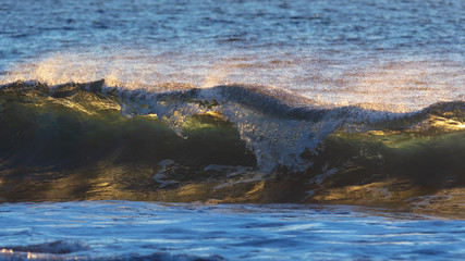 Sunrise over the sea with a breaking wave