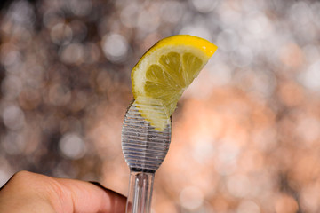 Closeup of barman hand putting lemon peel on a glass to prepare gin tonic cocktail.